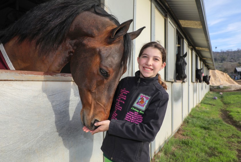 Portrait of Lindsay Heliker with her horse named Odyssey in his stall at Miller Equestrian Services and Valle Vista Farms.(Charlie Neuman/The San Diego Union-Tribune)