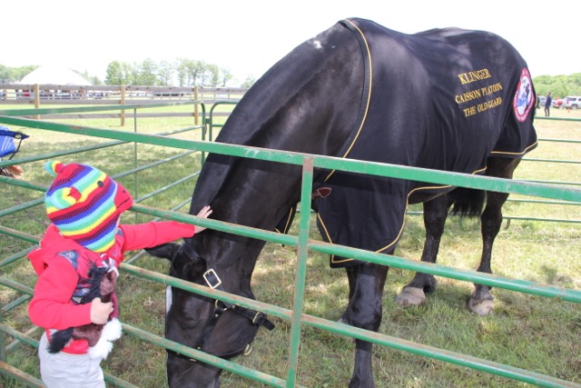 A young fan shows off her Klinger action figure to the TAPS mascot at the Potomac Hunt Races on May 15, 2016, courtesy of TAPS